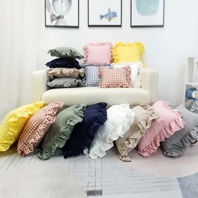 Colorful ruffled pillow collection displayed on a white sofa in a cozy living room.
