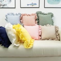 Vibrant ruffled decorative throw pillows in various pastel colors and patterns on a white sofa, perfect for enhancing home decor and comfort.