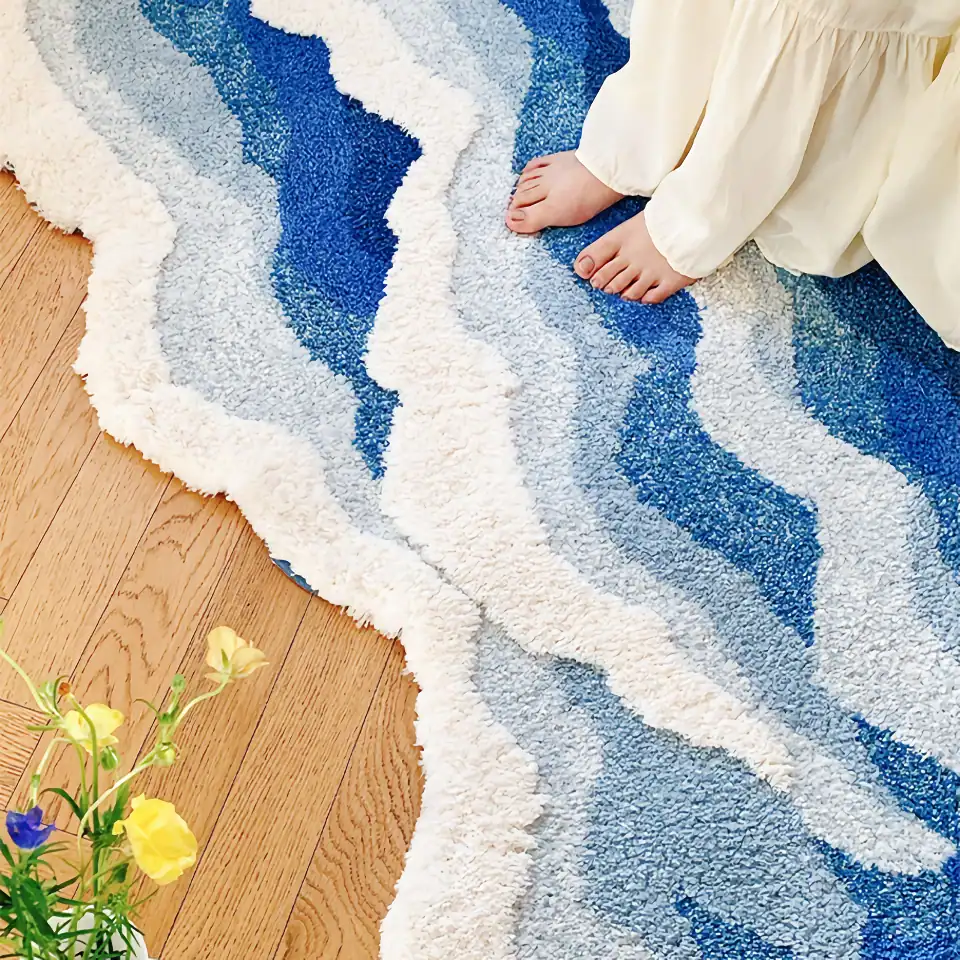 Soft blue and white textured area rug with wavy design on wooden floor, featuring child's bare feet and a small bouquet of yellow and purple flowers nearby.