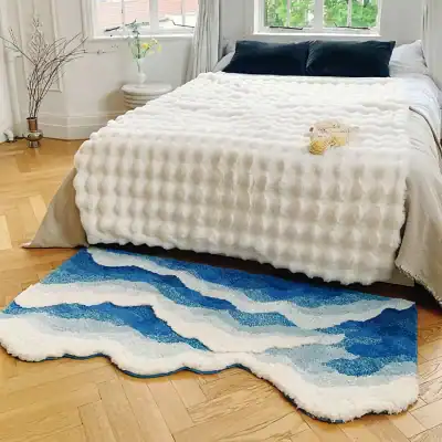 Plush white textured bedspread with dark blue pillows on a cozy bed in bright bedroom.
