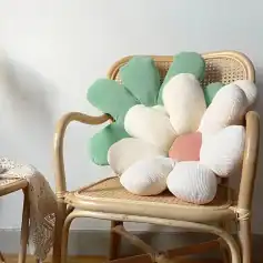 Pink and white flower-shaped cushion on a rattan chair.