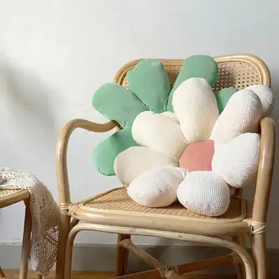 Pink and white flower-shaped cushion on a rattan chair.