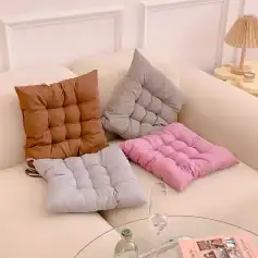 Plush tufted floor cushions in various pastel colors on cream sofa for cozy living space decoration.