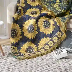 Vibrant sunflower patterned throw blanket with fringed edges on a sofa, ideal for home decor, offering a stylish and cozy accent.