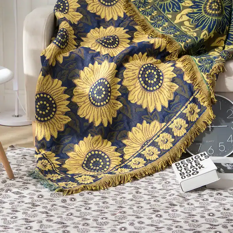 Vibrant sunflower patterned throw blanket with fringed edges on a sofa, ideal for home decor, offering a stylish and cozy accent.