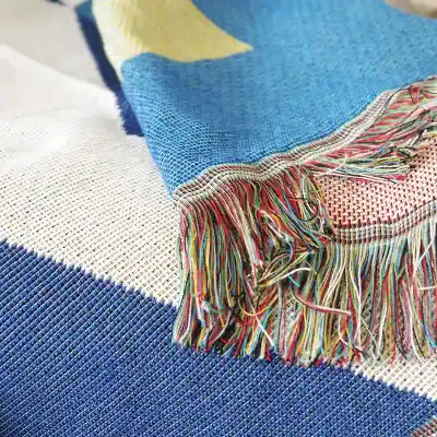 Colorful woven textile with fringed edges, ideal for home decor or fashion accessories, showcasing intricate craftsmanship and vibrant patterns.