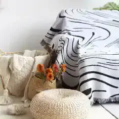 Luxurious black and white striped blanket draped over a cozy corner with woven baskets, textured cushions, and vibrant dried flowers creating an inviting, stylish ambiance.
