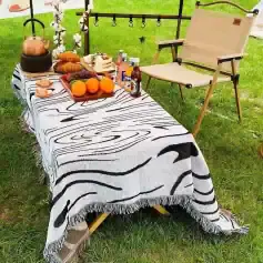 Elegant outdoor picnic setup with a zebra print tablecloth, fresh fruits, beverages, and cozy folding chair, perfect for outdoor leisure, dining, and social gatherings. Suitable for summer picnics and garden parties.