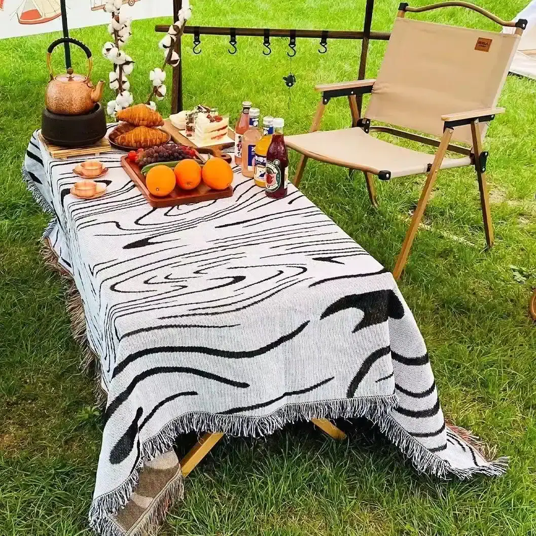 Elegant outdoor picnic setup with a zebra print tablecloth, fresh fruits, beverages, and cozy folding chair, perfect for outdoor leisure, dining, and social gatherings. Suitable for summer picnics and garden parties.