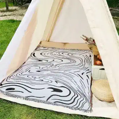 Stylish outdoor tent setup with cozy bedding, modern black-and-white geometric rug, and decorative accents for a relaxing experience at Monalisa Medical Store.