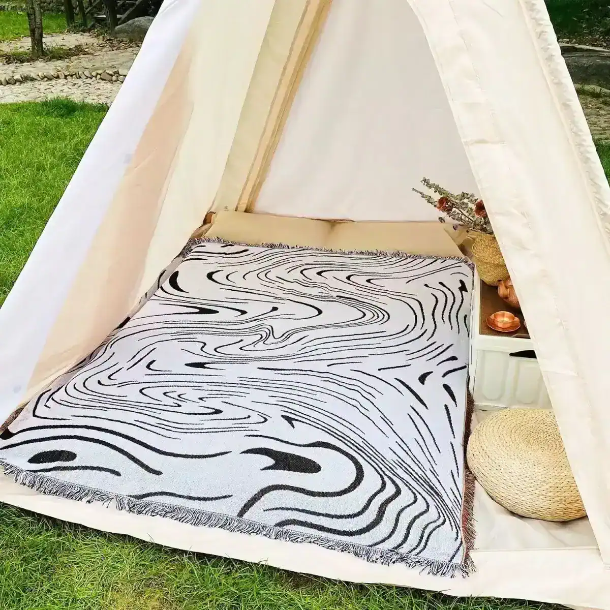 Stylish outdoor tent setup with cozy bedding, modern black-and-white geometric rug, and decorative accents for a relaxing experience at Monalisa Medical Store.