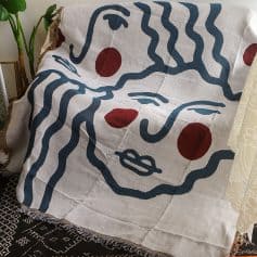 Vivid abstract face art throw blanket with bold blue lines and red accents, perfect for stylish decor and comfortable home accessories.