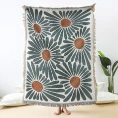 Bright floral patterned throw blanket with large daisy-style flowers in dark green and brown, perfect for home decor, lounging, or bedroom accents.