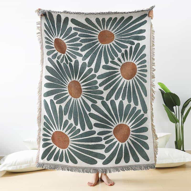 Bright floral patterned throw blanket with large daisy-style flowers in dark green and brown, perfect for home decor, lounging, or bedroom accents.