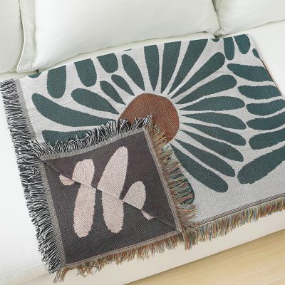 Vibrant floral patterned throw blanket on a white couch, enhances home decor with colorful, sunburst and butterfly motifs, perfect for cozy living room accents.