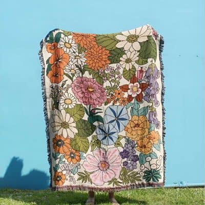 Bright floral-patterned blanket displayed outdoors on a clear day. Perfect for home decor, cozy cuddles, or as a stylish accessory, featuring vibrant, colorful flower designs.