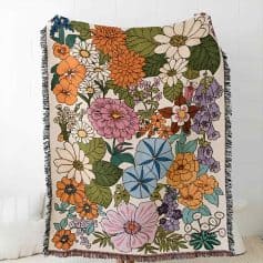 Vibrant floral patterned throw blanket with colorful flowers and green leaves, perfect for home decor or adding a touch of nature-inspired style.