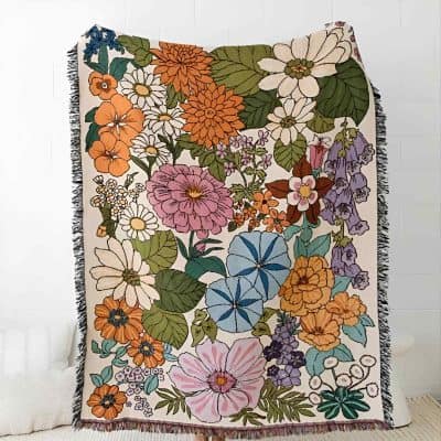 Vibrant floral patterned throw blanket with colorful flowers and green leaves, perfect for home decor or adding a touch of nature-inspired style.