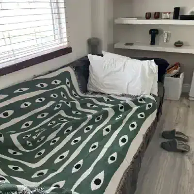 Couch with green eye pattern blanket and white pillow, modern living room decor, cozy home interior, comfortable seating area, Monalisa Medical store inspiration, stylish and inviting space.