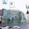 Colorful fish-patterned throw blanket draped over gray sofa in modern living room with framed artwork and houseplant, showcasing stylish home decor.