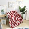 Vibrant red and white geometric throw blanket draped over a sofa in modern interior design setting.