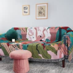 Vibrant colorful sofa with artistic embroidered throw, modern wall art decor, cozy pink pouf, and contemporary interior design perfect for stylish living rooms at Monalisa Store.