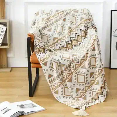 Vibrant geometric patterned throw blanket draped over an orange armchair in a modern living space. Perfect for home decor, adding warmth and style to your living room or bedroom.