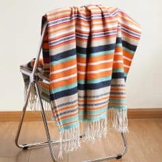 Colorful striped beach towel draped over a metal drying rack on wooden floor at Monalisa Store.