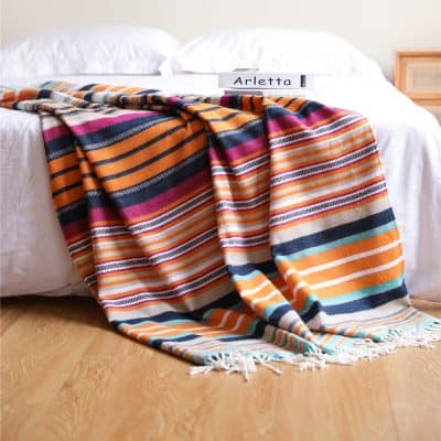 Colorful striped Turkish bath towel draped over a bed with a white coverlet, featuring a book titled