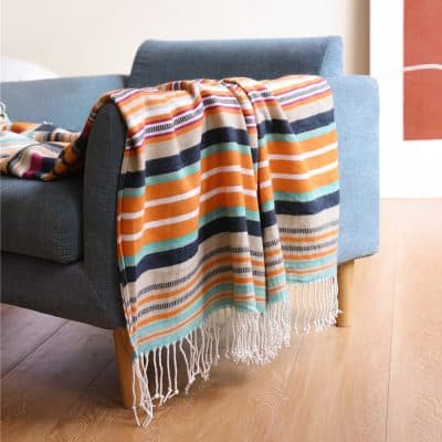 Bright striped throw blanket on a modern gray sofa, perfect for cozy home decor and relaxation. Bright, colorful, and soft, ideal for adding style and comfort to living rooms.