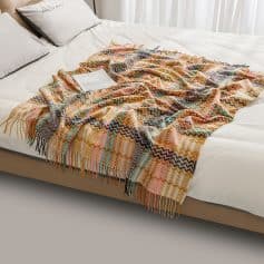 Colorful woven throw blanket on a bed, perfect for cozy bedroom decor and comfort, available at Monalisa Medical Store.