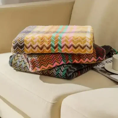 Luxurious colorful towels with zigzag patterns folded on a white sofa at Monalisa Store, perfect for enhancing your home decor or gift collection.