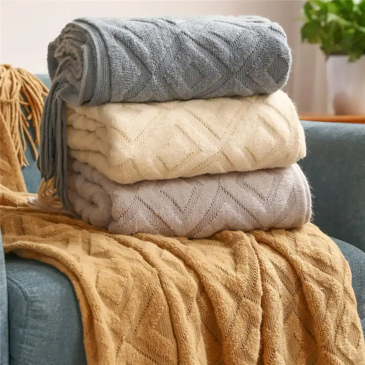 Soft woolen towels stacked on a sofa, featuring cozy textures and neutral colors, ideal for home comfort and decor.