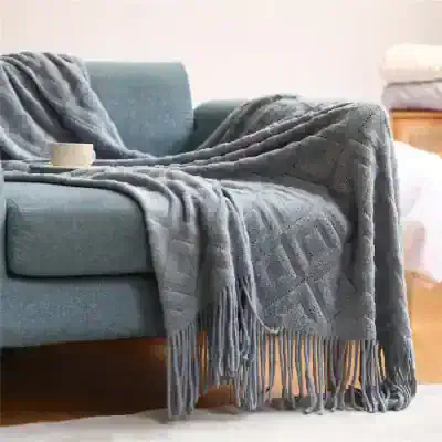 Luxurious gray knitted throw blanket draped over a cozy blue sofa, perfect for home decor, comfort, and warm moments. Ideal for living rooms and relaxation spaces.
