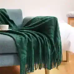 Luxurious emerald green throw blanket draped over a modern grey sofa, adding cozy elegance to living room decor - perfect for comfort and style.