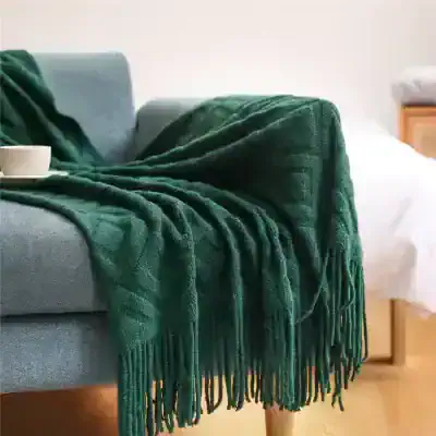 Luxurious emerald green throw blanket draped over a modern grey sofa, adding cozy elegance to living room decor - perfect for comfort and style.