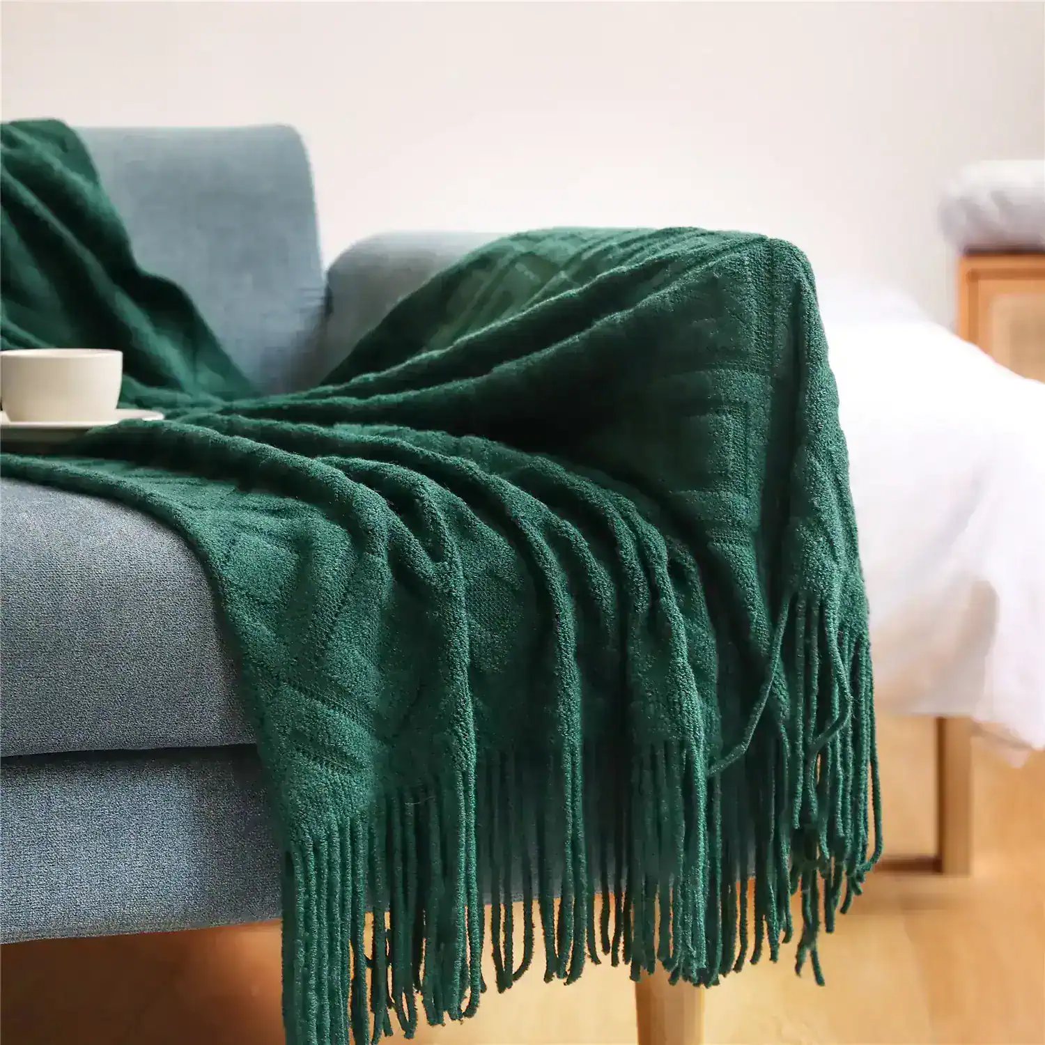 Luxurious emerald green throw blanket draped over a modern grey sofa, adding cozy elegance to living room decor - perfect for comfort and style.