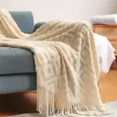 Soft beige decorative throw with geometric patterns and fringed edges, perfect for adding cozy style to your sofa or armchair.
