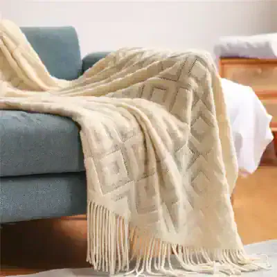 Soft beige decorative throw with geometric patterns and fringed edges, perfect for adding cozy style to your sofa or armchair.