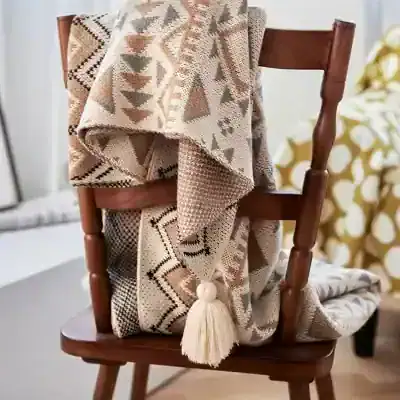 Cozy woven throw blanket with tassel draped over wooden chair for home decor.