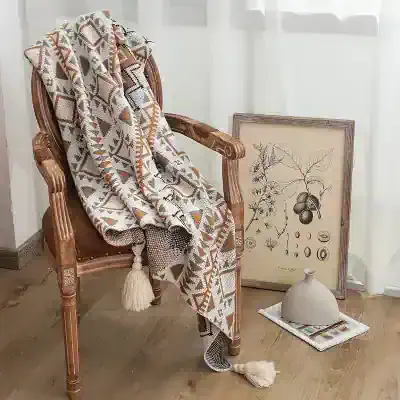 Luxurious woven throw blanket with geometric patterns draped over vintage wooden armchair, surrounded by botanical artwork and ceramic vase for elegant household decor, ideal for home aesthetics.