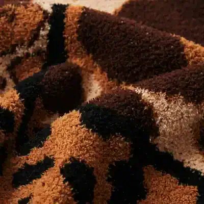 Soft plush slippers with beige, black, and dark brown textured fabric, perfect for cozy comfort and homewear.