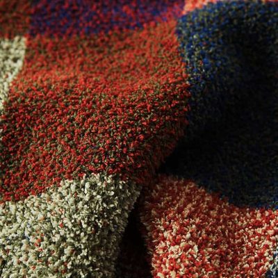 Colorful textured plush carpet in red, gray, white, blue, and black, showcasing high-quality craftsmanship, perfect for enhancing interior decor and comfort in homes or offices.