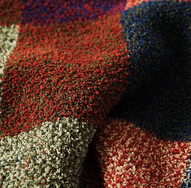Colorful textured plush carpet in red, gray, white, blue, and black, showcasing high-quality craftsmanship, perfect for enhancing interior decor and comfort in homes or offices.
