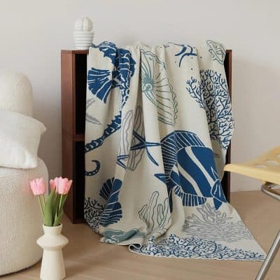 Vibrant beach-inspired woven throw blanket with navy blue coral and shell patterns, perfect for coastal or modern home decor.