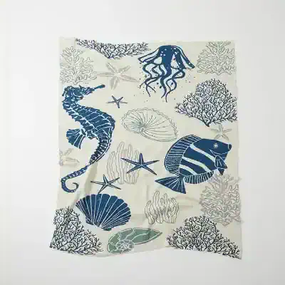 Vibrant ocean-themed fabric with seahorses, fish, coral, and marine life illustrations in blue and beige tones, ideal for home decor or accessories.