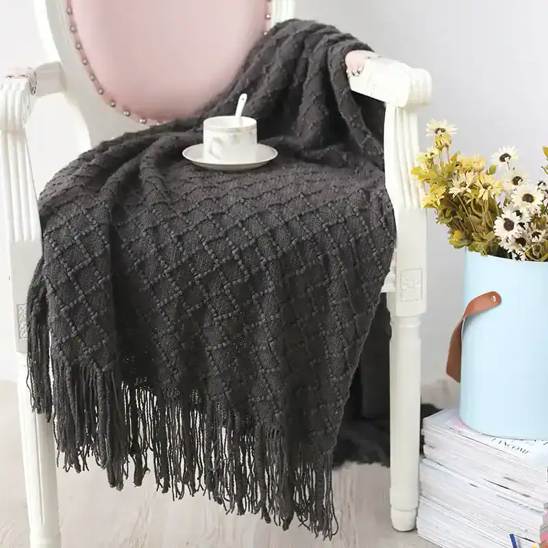 Luxury black knit shawl with fringes displayed on a white wooden chair at Monalisa Store, ideal for fashionable winter accessories and elegant women’s scarves, perfect for enhancing your style.