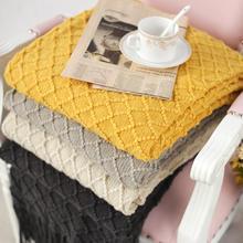 Soft, textured towels in yellow, beige, and black stacked on a bed with a cup of tea and a newspaper, showcasing luxurious bathroom or spa accessories.
