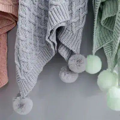 Soft cable-knit sweaters with fluffy pom-poms in pastel colors at Monalisa Store, perfect for cozy winter fashion and outdoor warmth.