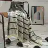 Luxurious black and white patterned throw blanket with tassels, perfect for home decor or cozying up in style.